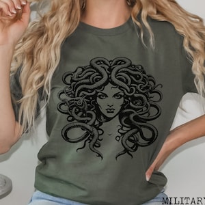 May include: A green t-shirt with a black graphic print of Medusa, a mythical Greek figure with snakes for hair.