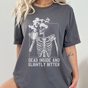 May include: A gray t-shirt with a skeleton holding a cup of coffee and the text "Dead inside and slightly bitter".