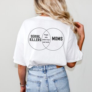 Puede incluir: Camiseta blanca con un gr&aacute;fico negro de un diagrama de Venn. El c&iacute;rculo izquierdo dice "Asesinos en serie", el c&iacute;rculo derecho dice "Mam&aacute;s", y la secci&oacute;n superpuesta dice "Personas que recolectan cabello y dientes".