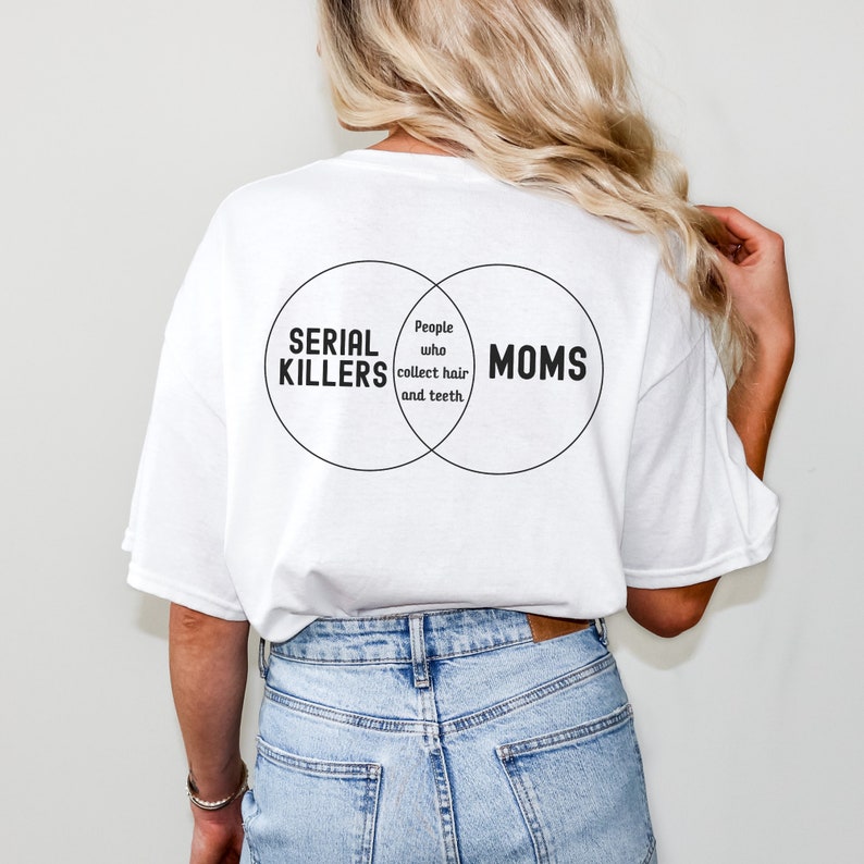 Puede incluir: Camiseta blanca con un gr&aacute;fico negro de un diagrama de Venn. El c&iacute;rculo izquierdo dice "Asesinos en serie", el c&iacute;rculo derecho dice "Mam&aacute;s", y la secci&oacute;n superpuesta dice "Personas que recolectan cabello y dientes".