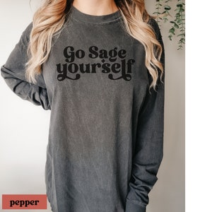 May include: A dark grey long-sleeved t-shirt with the text "Go Sage yourself" printed in black.