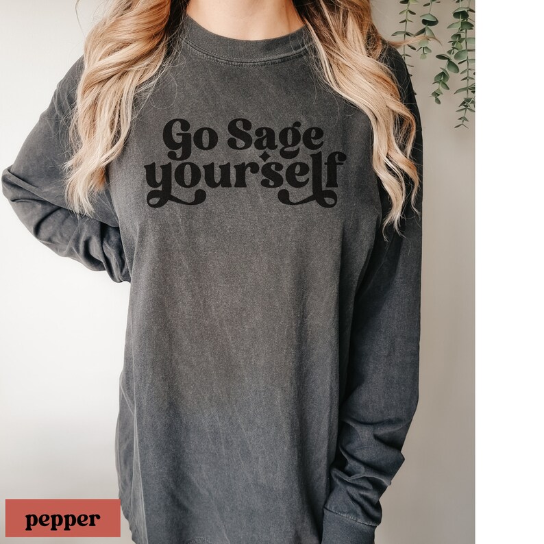 May include: A dark grey long-sleeved t-shirt with the text "Go Sage yourself" printed in black.