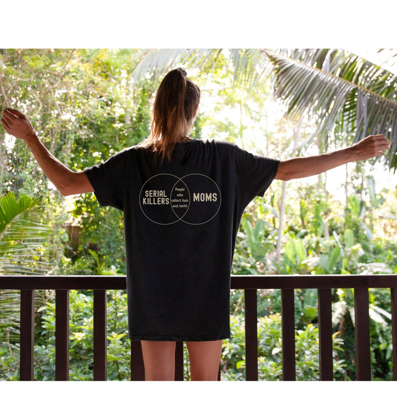 Puede incluir: Una camiseta negra con un gr&aacute;fico de diagrama de Venn que dice "Asesinos en serie" y "Mam&aacute;s" con la secci&oacute;n superpuesta que dice "Personas que coleccionan cabello y dientes".