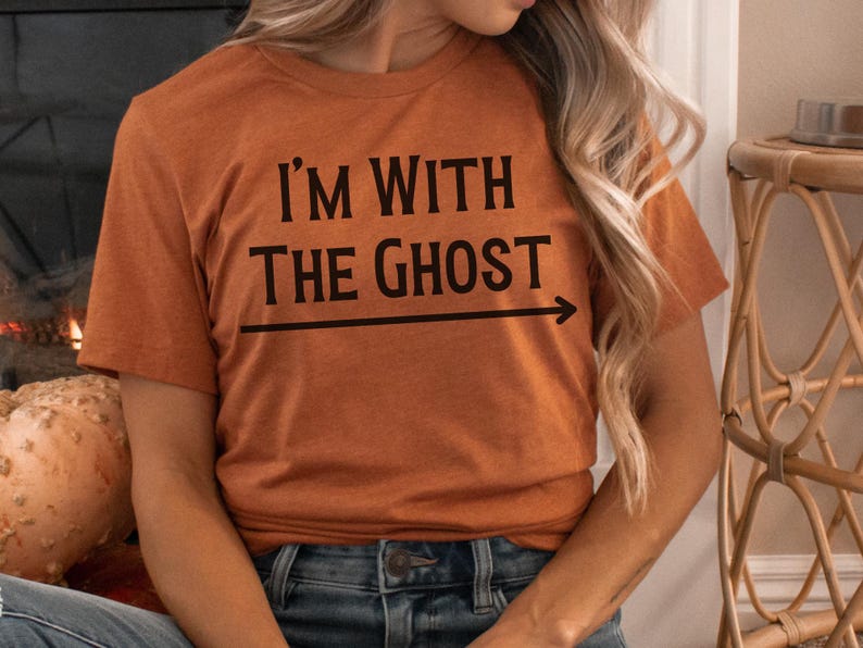 May include: A rust-colored t-shirt with the text "I'm with the ghost" and an arrow pointing to the right.