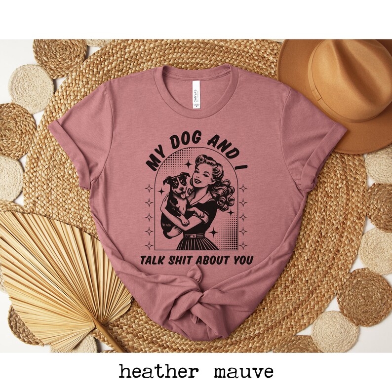Op de afbeelding: Heather mauve t-shirt met een retro afbeelding van een vrouw die een hond vasthoudt. De afbeelding zegt "My Dog and I Talk Shit About You".