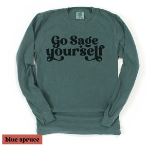 May include: A long-sleeved t-shirt in a blue-green color with the text "Go Sage yourself" printed in black.