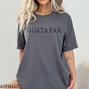 May include: A gray t-shirt with the text "GUATAFAK" printed in black on the front.