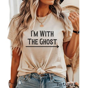 May include: A beige t-shirt with the text "I'm with the ghost" and an arrow pointing to the right.