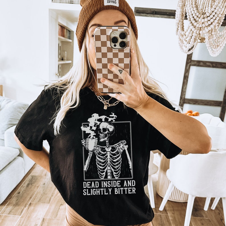 May include: Black t-shirt with a skeleton graphic holding a cup of coffee. The text "Dead inside and slightly bitter" is printed below the graphic.