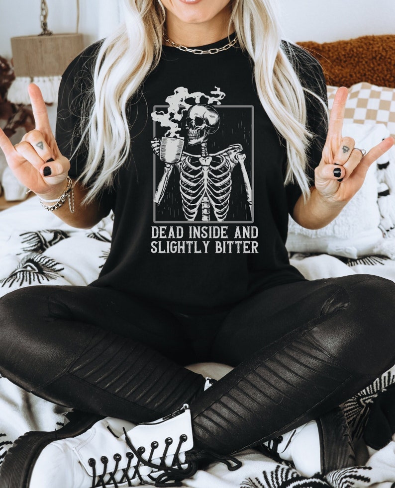 May include: Black t-shirt with a graphic of a skeleton holding a coffee mug. The text "Dead inside and slightly bitter" is printed below the graphic.