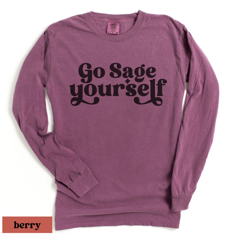 May include: A long-sleeved t-shirt in a berry color with the text "Go Sage Yourself" printed in black.