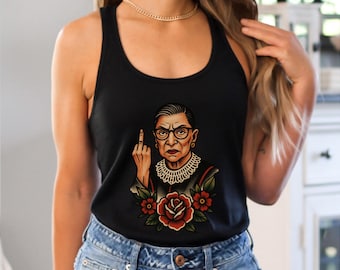 Pode incluir: Regata preta com uma ilustração em estilo tatuagem de uma mulher com óculos, gola de renda branca e expressão severa, mostrando o dedo do meio. Rosas vermelhas e folhas verdes circundam a imagem.