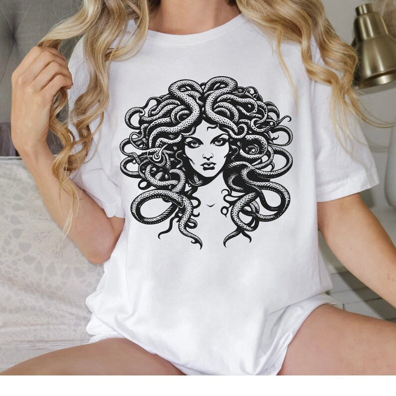 May include: White t-shirt with a black and white graphic print of Medusa, a mythical Greek figure with snakes for hair.