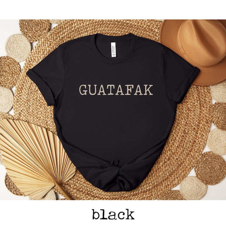 May include: Black t-shirt with the text "GUATAFAK" printed in a light beige color.