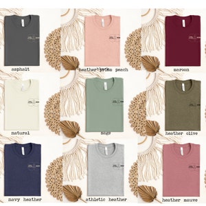 Puede incluir: Un conjunto de diez camisetas de diferentes colores, incluyendo asfalto, melocot&oacute;n de prisma de color, granate, natural, salvia, oliva jaspeado, azul marino jaspeado, jaspeado atl&eacute;tico y malva jaspeado. Cada camiseta presenta un dise&ntilde;o gr&aacute;fico simple con el texto "Soul Sisters" y "Mom" en un c&iacute;rculo.