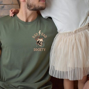 May include: A green t-shirt with a skull and snake graphic and the text "Rad Dad Society".
