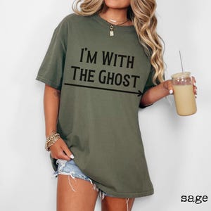 May include: Sage green oversized t-shirt with the text "I'm with the ghost" and an arrow pointing to the right.