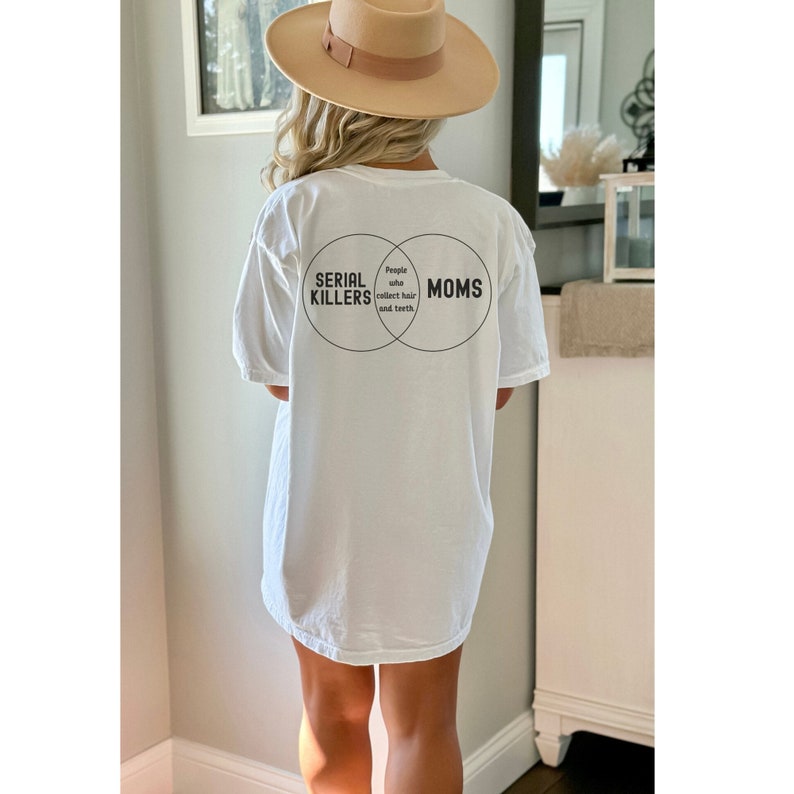 Puede incluir: Camiseta blanca con un gr&aacute;fico de dos c&iacute;rculos superpuestos. El c&iacute;rculo izquierdo dice "Serial Killers" y el c&iacute;rculo derecho dice "Moms". La secci&oacute;n superpuesta dice "Personas que recolectan cabello y dientes".