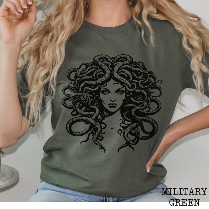 May include: A green t-shirt with a black graphic print of Medusa, a mythical Greek figure with snakes for hair.