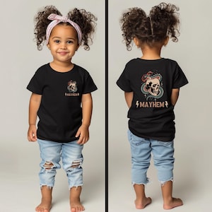 以下が含まれることがあります： 黒いTシャツに、頭蓋骨とヘビのグラフィックと「MAYHEM」の文字が背中にプリントされています。Tシャツは、薄いブルーのジーンズを履いた子供が着用しています。