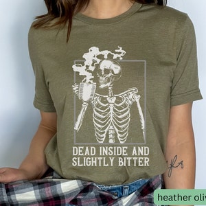 May include: A green t-shirt with a skeleton holding a cup of coffee and the text "Dead inside and slightly bitter".