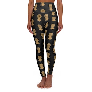 May include: Black yoga leggings with a gold pineapple print. The leggings are high-waisted and have a fitted silhouette.