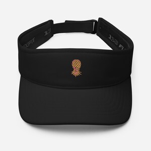 May include: Black visor with a Flexfit design. The visor features an embroidered pineapple design in shades of tan, pink, and green. The text "110 Flexfit" is printed on the side. This visor is a stylish accessory for sun protection.