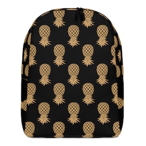 May include: Black backpack with a repeating pattern of gold pineapples.