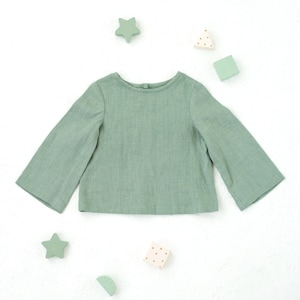 Peut inclure: Un chemisier à manches longues de couleur vert sauge avec un col rond. Le chemisier est fait d'un tissu doux et léger et a une coupe décontractée.