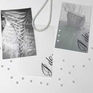 Puede incluir: Dos tarjetas blancas con el texto "I do." impreso en cursiva negra. Las tarjetas est&aacute;n decoradas con un collar de perlas y peque&ntilde;as perlas blancas esparcidas a su alrededor. Una tarjeta tiene una foto en blanco y negro de un vestido de novia.