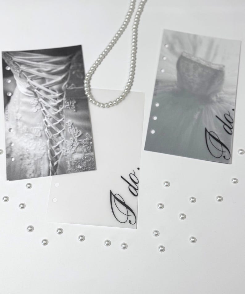 Puede incluir: Dos tarjetas blancas con el texto "I do." impreso en cursiva negra. Las tarjetas est&aacute;n decoradas con un collar de perlas y peque&ntilde;as perlas blancas esparcidas a su alrededor. Una tarjeta tiene una foto en blanco y negro de un vestido de novia.