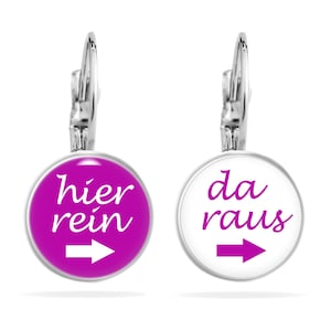 Könnte beinhalten: Ein Paar silberne Ohrringe mit einem runden, weißen und rosafarbenen Glasanhänger. Die Anhänger haben einen weißen Pfeil, der nach rechts zeigt, und den Text "hier rein" in rosa auf dem rosafarbenen Anhänger und "da raus" in schwarz auf dem weißen Anhänger.