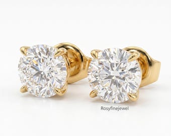 May include: A pair of round-cut diamond stud earrings set in gold. The diamonds are clear and sparkling, held in place by four prongs. The earrings are displayed on a white background. The text "Rosyfinejewel" is visible.