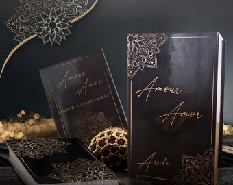 May include: A set of black and gold tarot cards with a guidebook titled "Amour Amor Livre d'Accompagnement". The cards feature intricate mandala designs.
