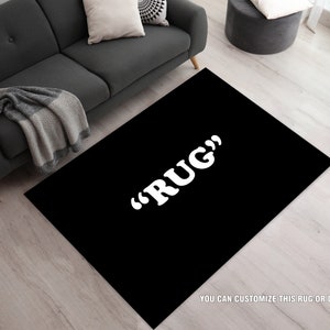May include: A black rug with the text "RUG" in white letters. The rug is on a light wood floor.