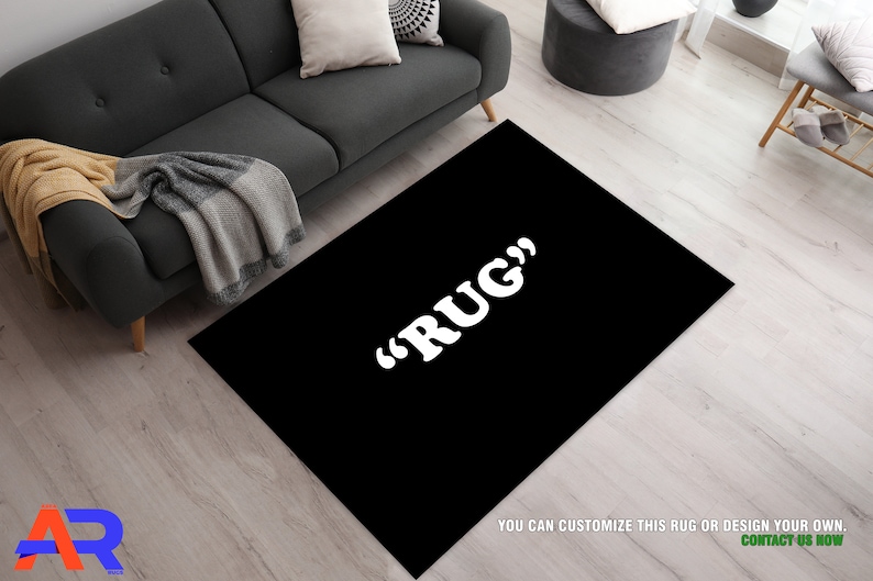 May include: A black rug with the text "RUG" in white letters. The rug is on a light wood floor.