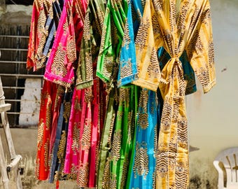 Può includere: Una fila di accappatoi colorati e fantasia appesi a un filo. Gli accappatoi presentano un motivo a righe di tigre in vari colori, tra cui rosso, rosa, verde, blu e giallo. Gli accappatoi sono realizzati in un tessuto leggero.
