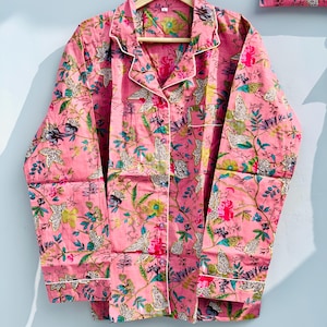 Pu&ograve; includere: Set pigiama rosa con fantasia floreale. Il set comprende una camicia con bottoni con finiture bianche e una tasca abbinata, insieme a pantaloni coordinati. Il tessuto presenta un disegno di fiori, foglie e stampe animalier.