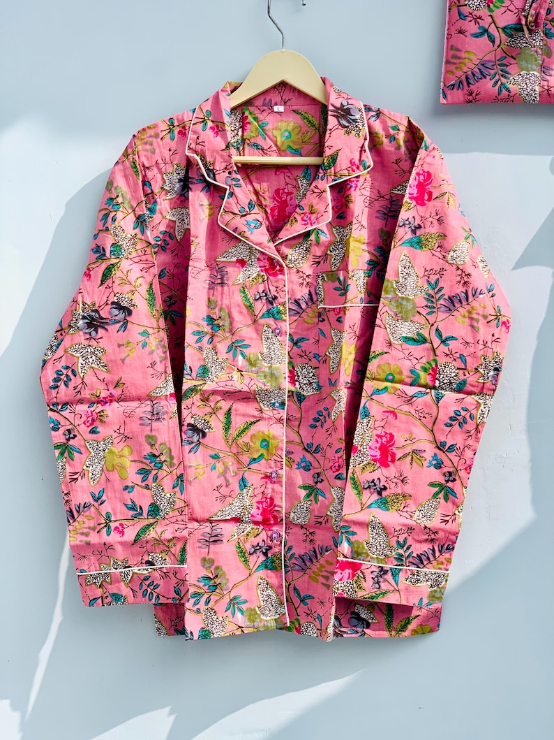 Pu&ograve; includere: Set pigiama rosa con fantasia floreale. Il set comprende una camicia con bottoni con finiture bianche e una tasca abbinata, insieme a pantaloni coordinati. Il tessuto presenta un disegno di fiori, foglie e stampe animalier.