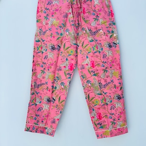 Pu&ograve; includere: Pantaloni da pigiama rosa con un motivo floreale con uccelli e fogliame nei toni del verde, blu e bianco. I pantaloni hanno un girovita con coulisse e bordatura bianca. Il tessuto &egrave; leggero.