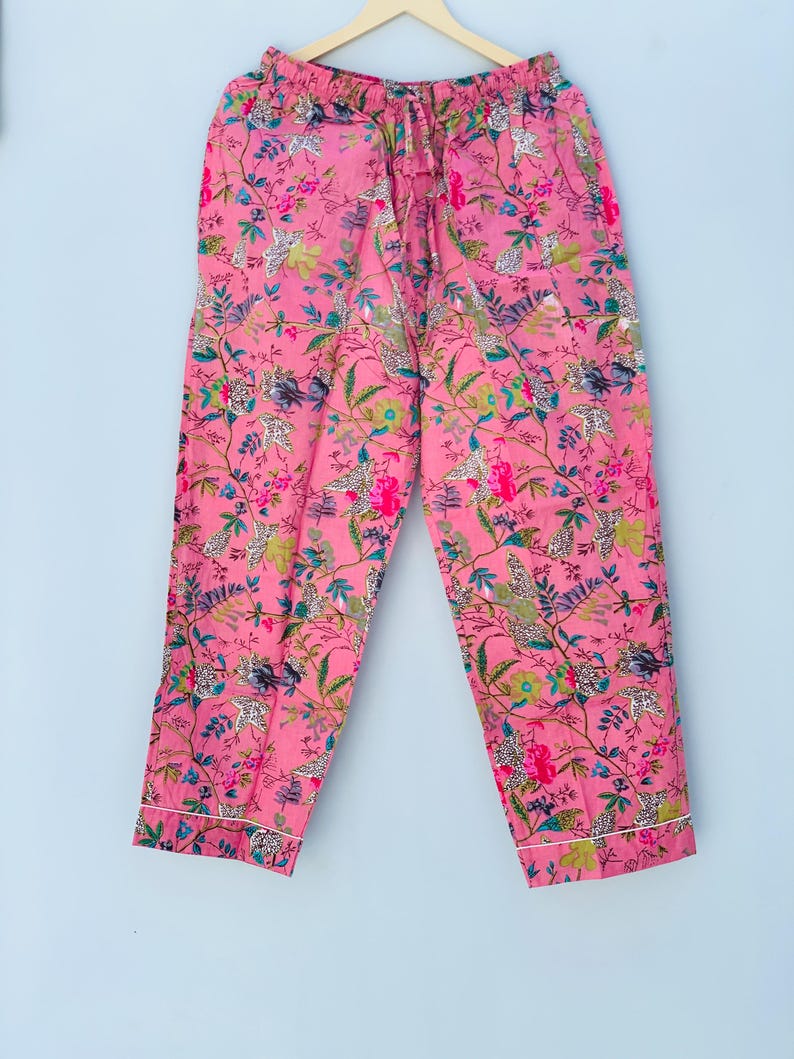 Pu&ograve; includere: Pantaloni da pigiama rosa con un motivo floreale con uccelli e fogliame nei toni del verde, blu e bianco. I pantaloni hanno un girovita con coulisse e bordatura bianca. Il tessuto &egrave; leggero.