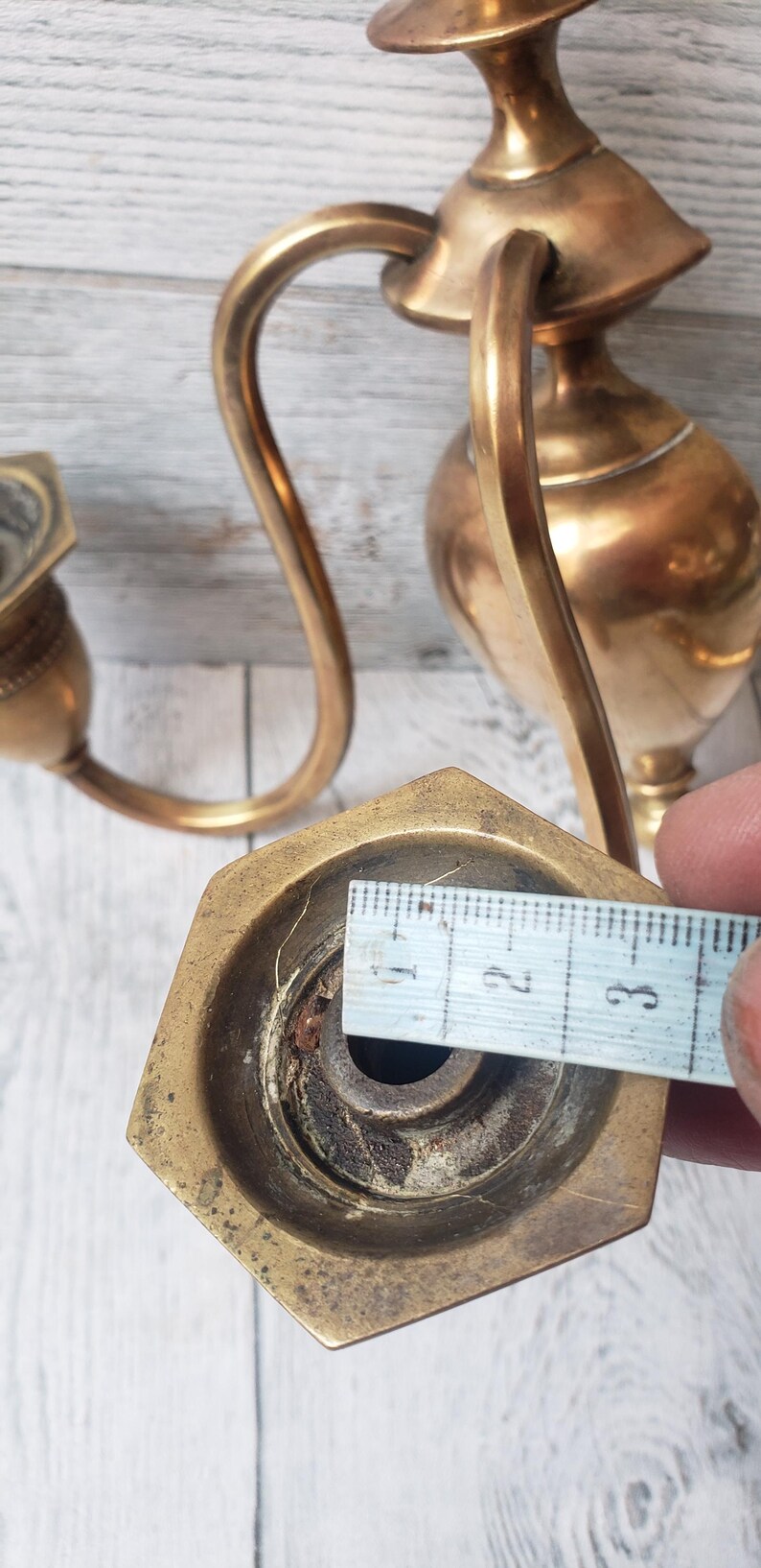 May include: Vintage brass candle holder with a curved arm and hexagonal base. The base measures approximately 1.25 inches across. The candle holder has a tarnished, aged appearance, suggesting it is antique.