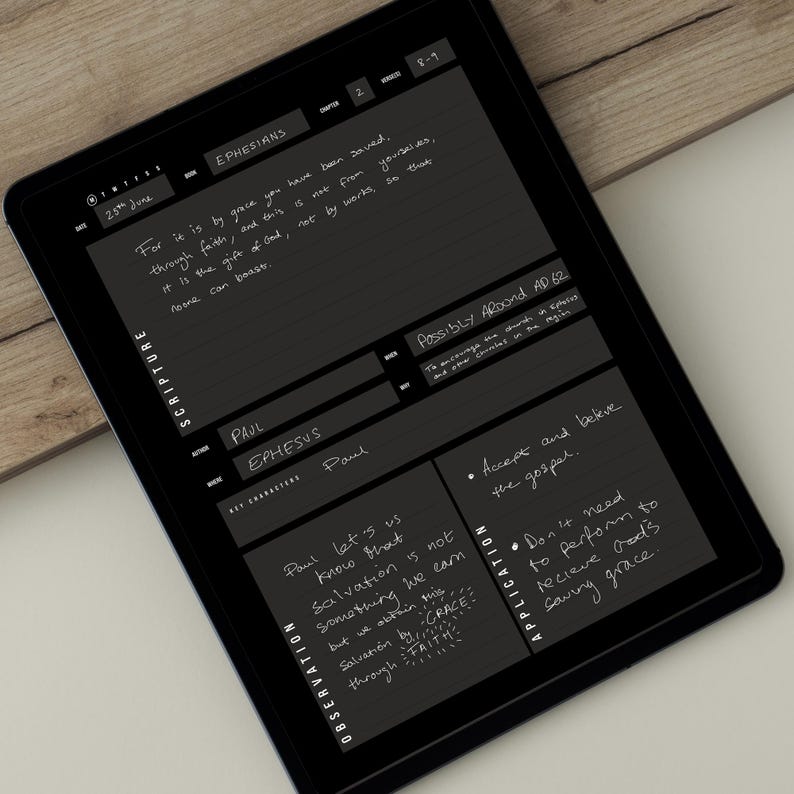 May include: A black tablet displaying handwritten notes on scripture from Ephesians. The text includes phrases like "by grace you have been saved" and "Salvation by grace through faith." The tablet is on a wooden surface.