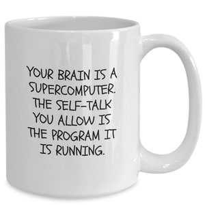 May include: White ceramic coffee mug with black text that reads: "Your brain is a supercomputer. The self-talk you allow is the program it is running."