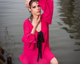 Pink pleated dress with long sleeves and deep neckline