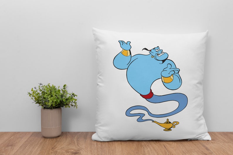 May include: White pillow with a blue genie character from the movie Aladdin. The genie is smiling and holding his hand up. He is wearing a red sash and a gold bracelet. The genie is coming out of a gold lamp.