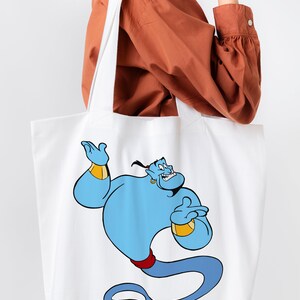 May include: White canvas tote bag with a blue genie character from Disney's Aladdin. The genie is holding a gold lamp and has a mischievous expression.