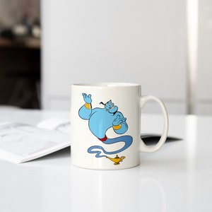 May include: White ceramic mug with a blue genie character from Disney's Aladdin. The genie is holding a magic lamp and is surrounded by a blue smoke trail.