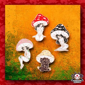 Puede incluir: Conjunto de cuatro pines de esmalte que representan un hongo con una persona sentada dentro. Los hongos son de diferentes colores, incluyendo rojo, negro, rosa y amarillo. Cada pin tiene un contorno dorado.