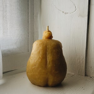 May include: A yellow pear-shaped candle with a textured surface.
